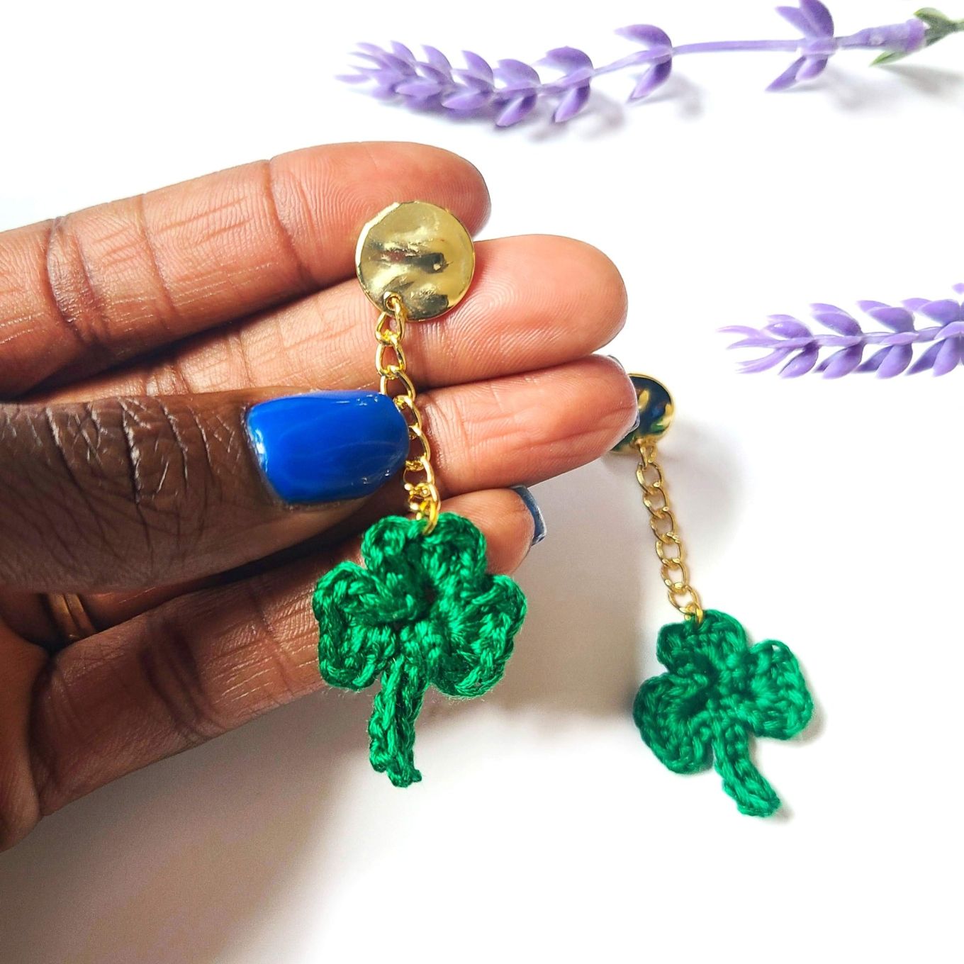 Model holding a pair of shamrock dangle earrings.