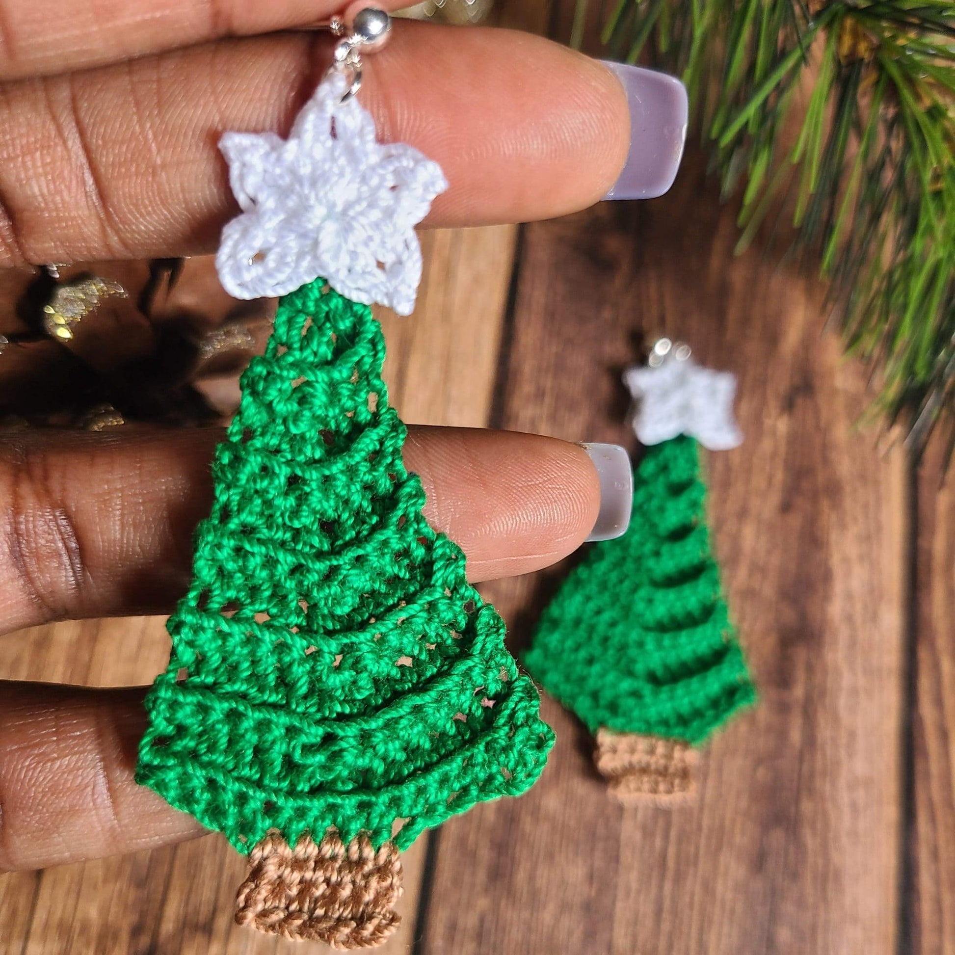 Christmas Tree dangle earrings in hand to show the size.