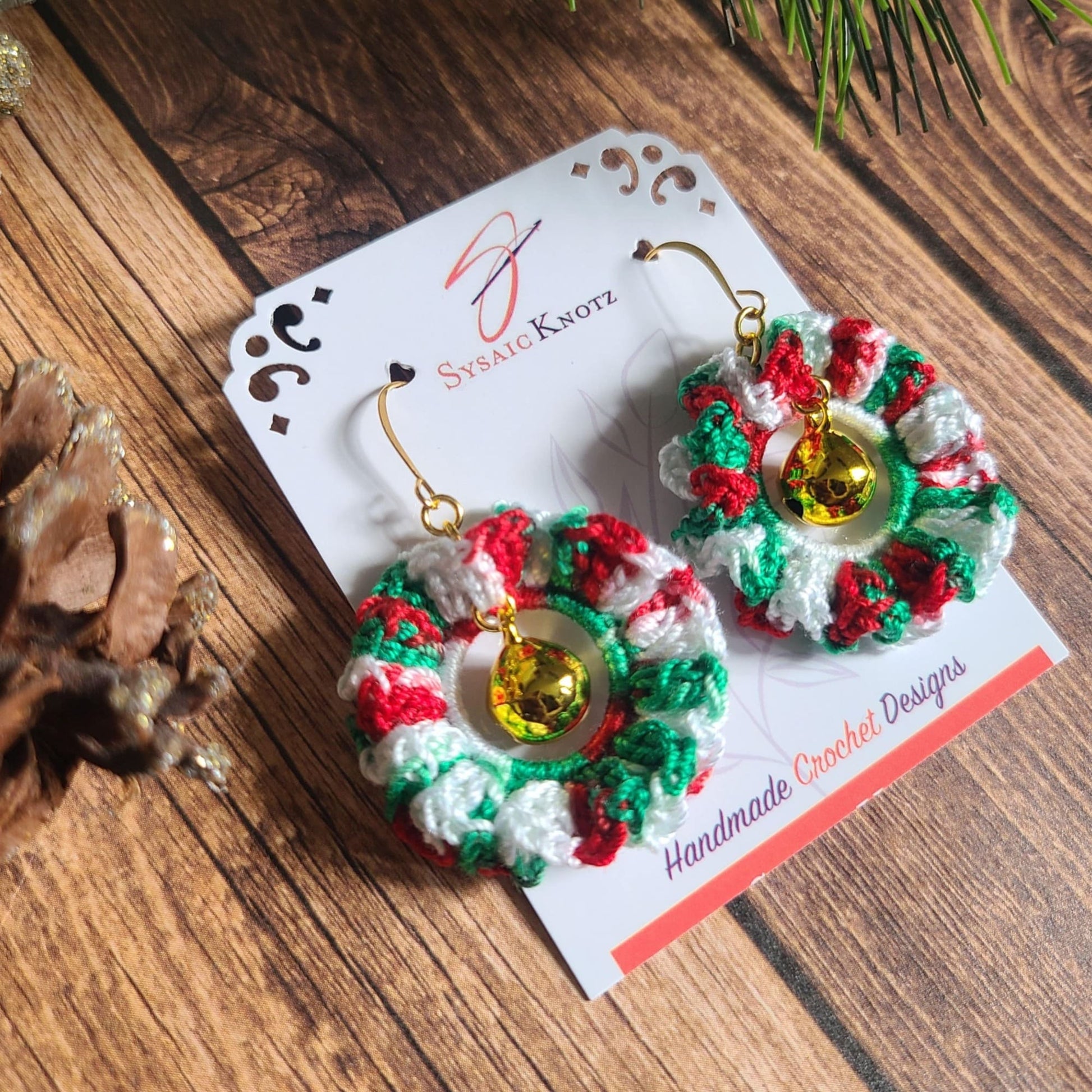 Christmas Wreath earrings on wooden background with pine cone.