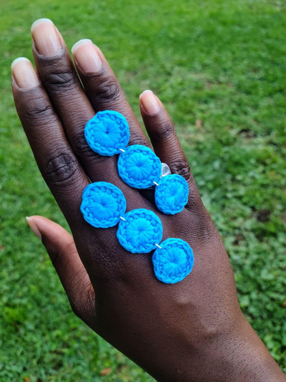 Model's hand with a pair of baby blue triple circle dangle earrings.