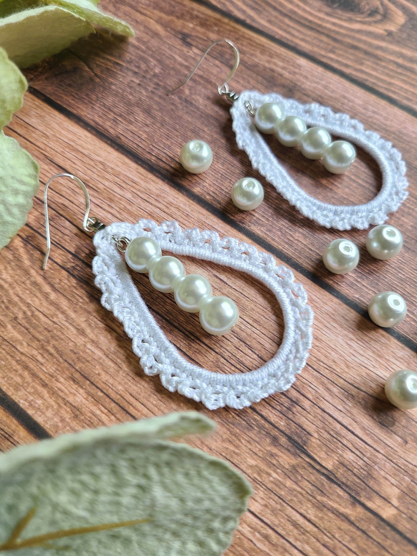 Laced crochet earrings in tear drop shape with a line of pearls in the middle.