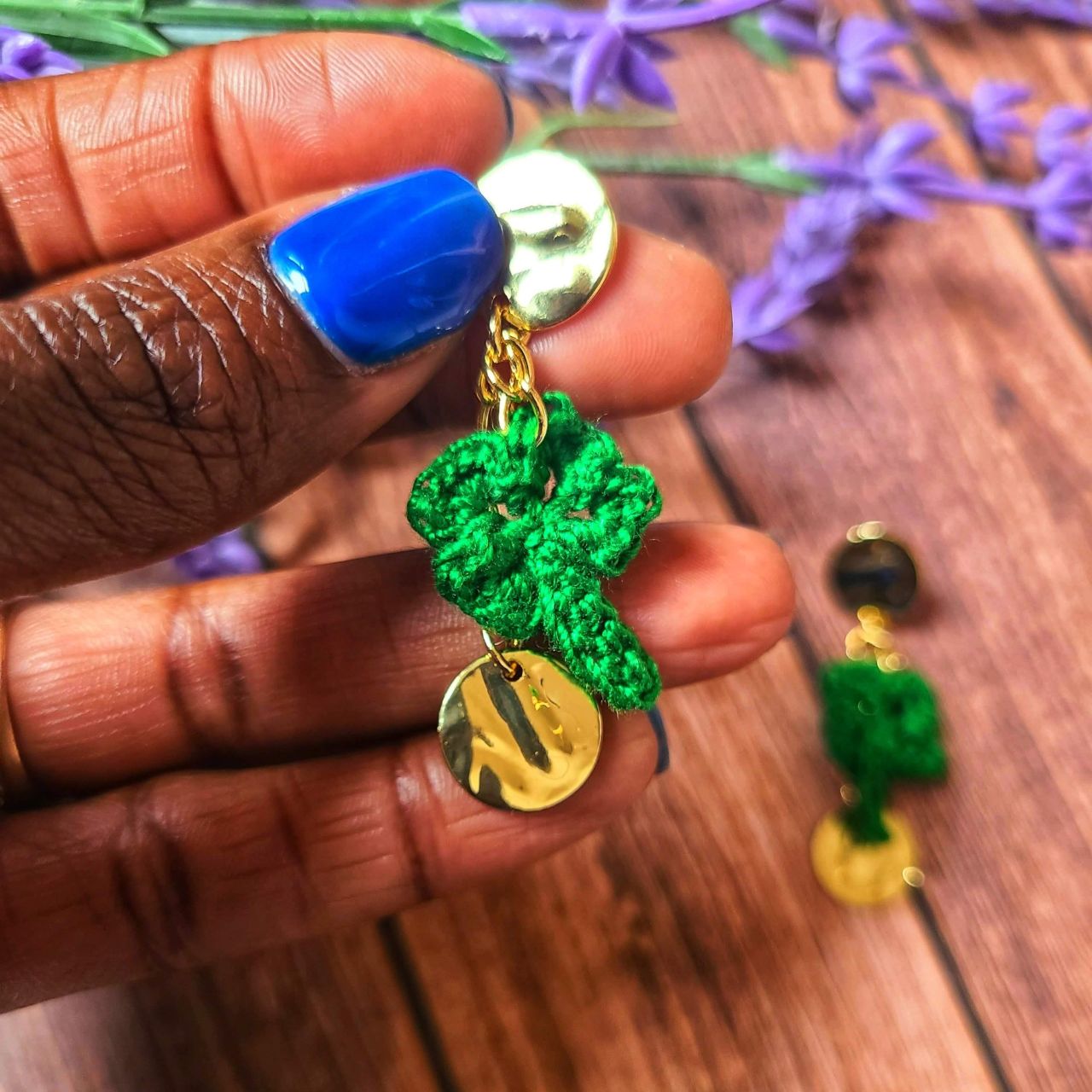 A model holding a pair of dangle shamrock earrings