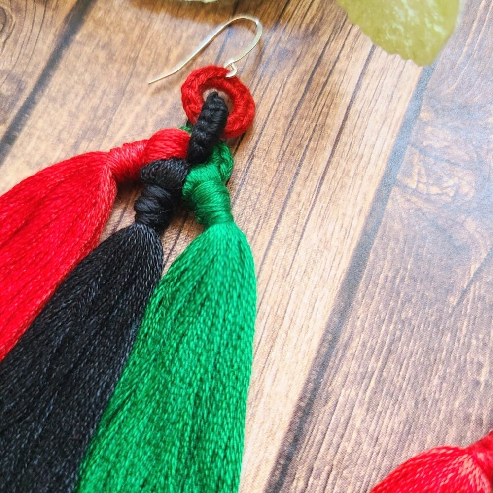 A close up of the tassel earrings in red, black, and green.