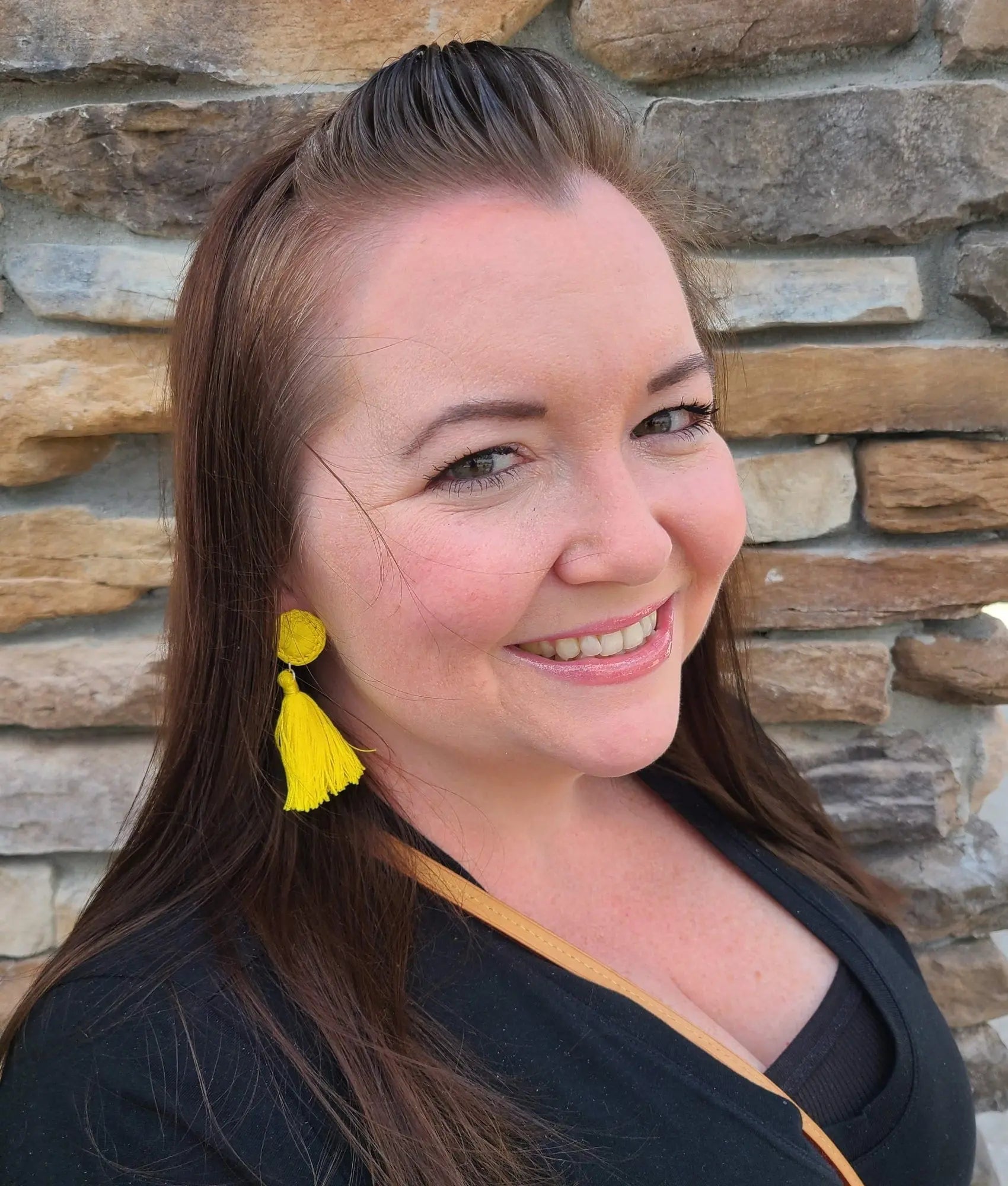 Model wearing yellow tassel earrings.