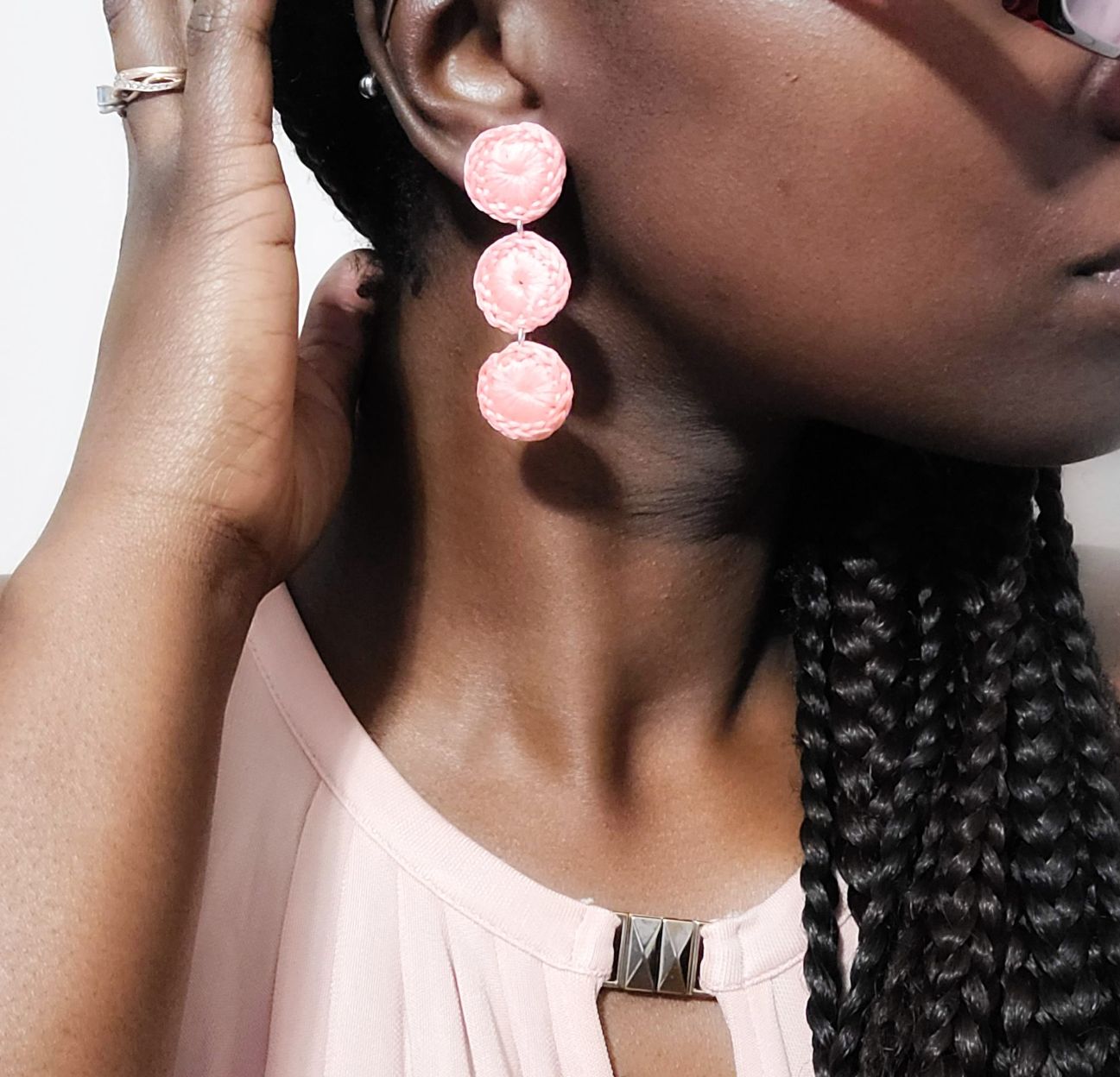 Model wearing a pair of pink triple circle dangle earrings.