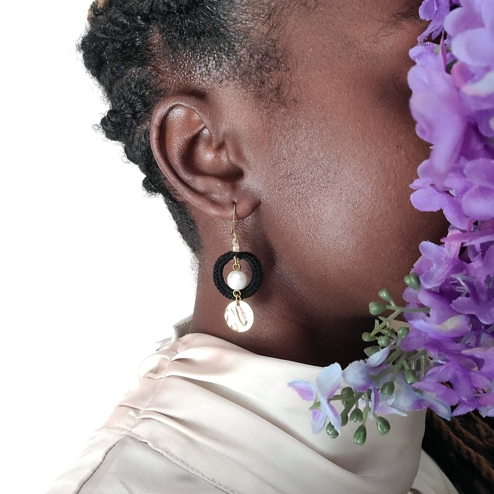 Model wearing drop and dangle pearl earrings with gold.