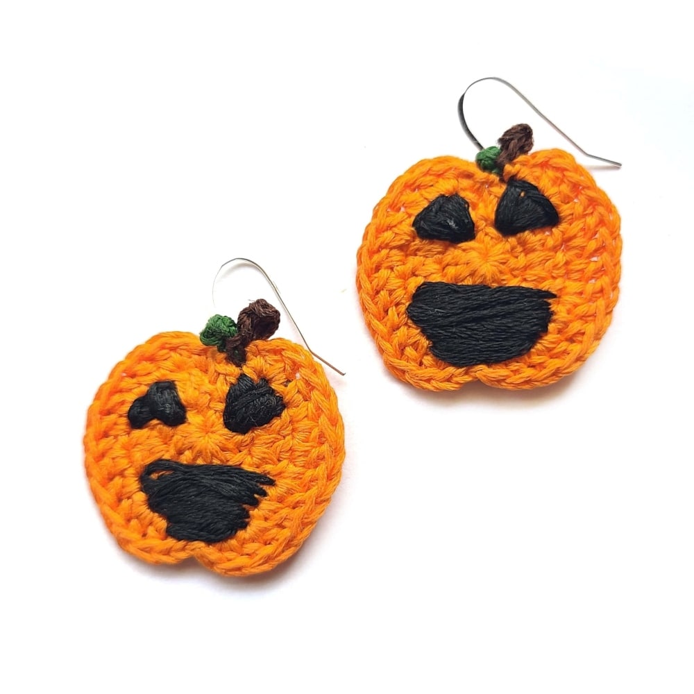 An up close view of Jack O Lantern earrings on a white background.
