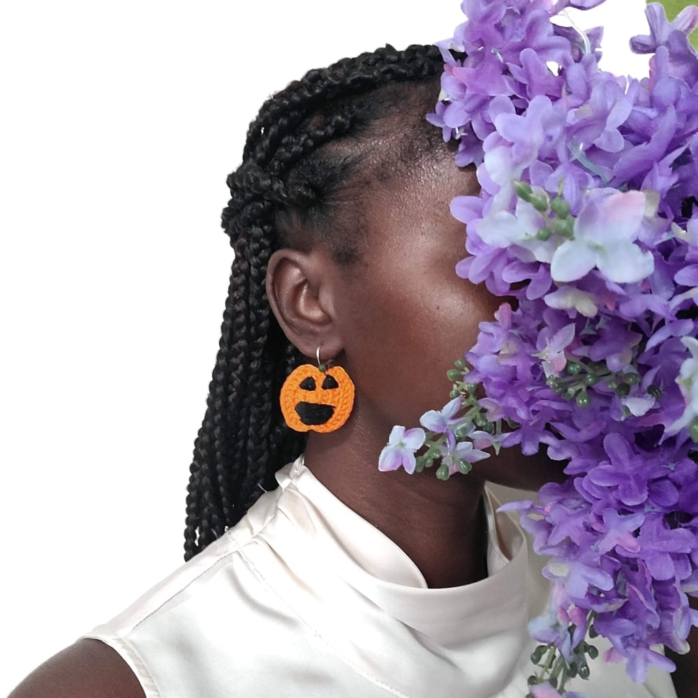Model wearing a pair of Jack O lantern earrings to display the size.